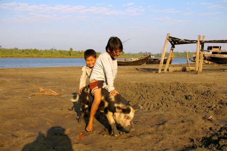 Jahrmarkt in Myanmar: Kinder auf einem Schwein in der Nähe von Chaung Tha