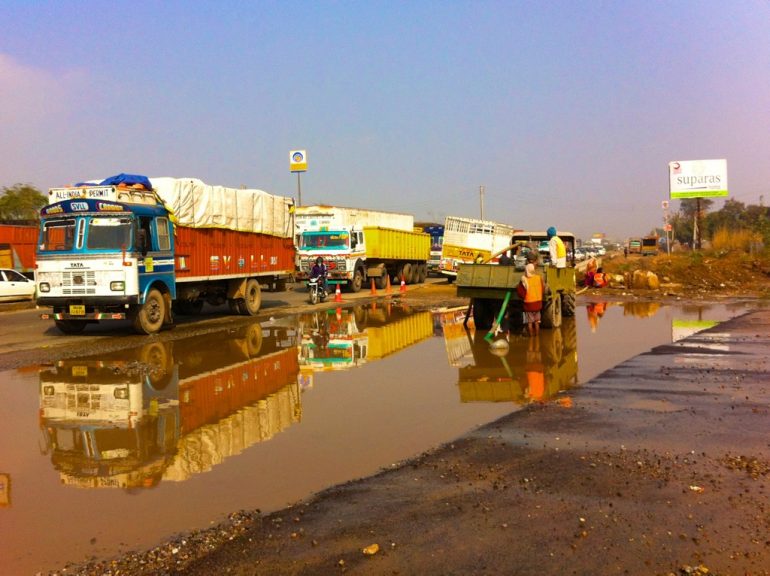 Renting an Enfield in India: Trucks on a wet road
