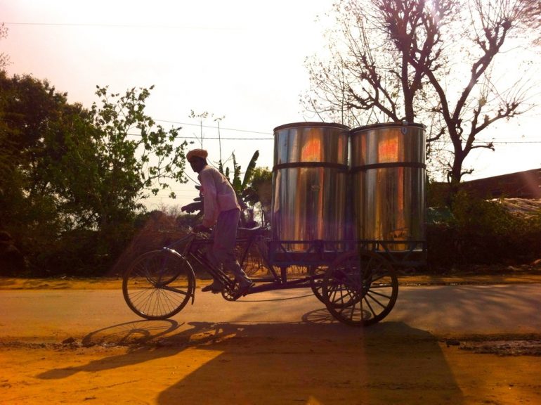 Mann auf einem Fahrrad mit Metallfässern