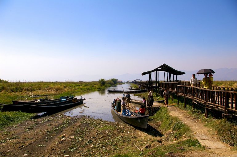 Boote  und Menschen neben einer Brücke in Myanmar