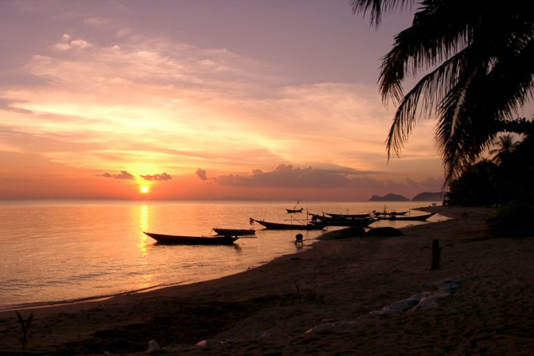 Günstig reisen: Boote im Sonnenuntergang am Strand