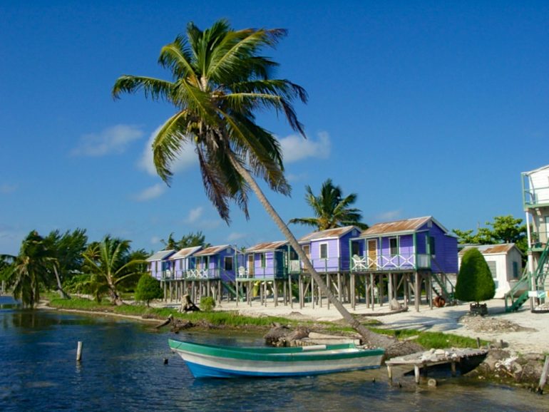 Boot und Häuser mit Palmen am Meer