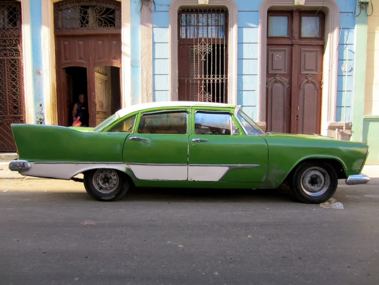 Cuba cars: Green US classic car in front of an old house