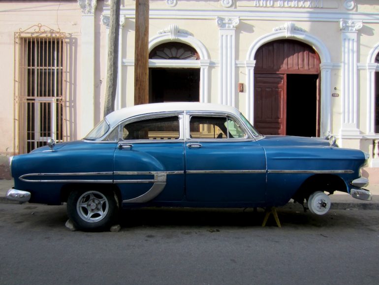 Blauer Oldtimer vor kubanischem Haus