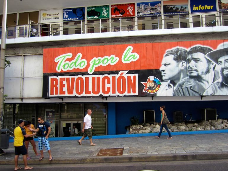 Menschen vor Revolutions-Schild in Havanna