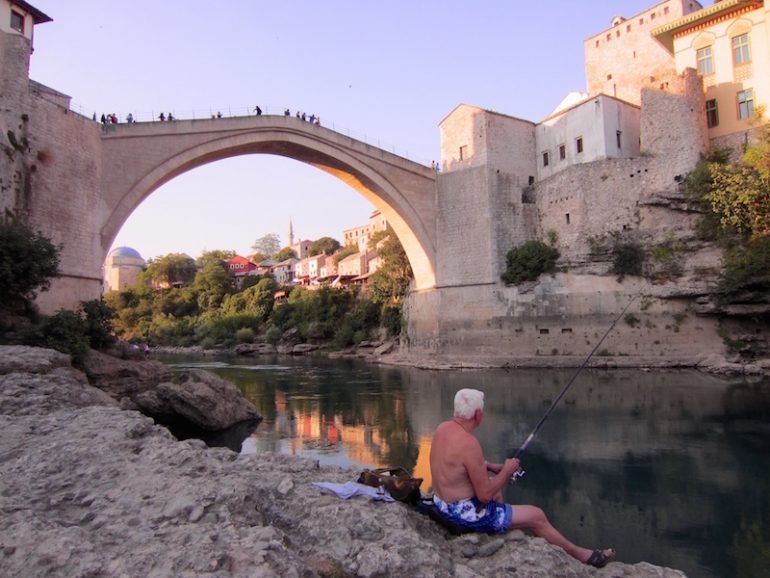 Best road trips: Man in front of the Stari Most bridge in Mostar