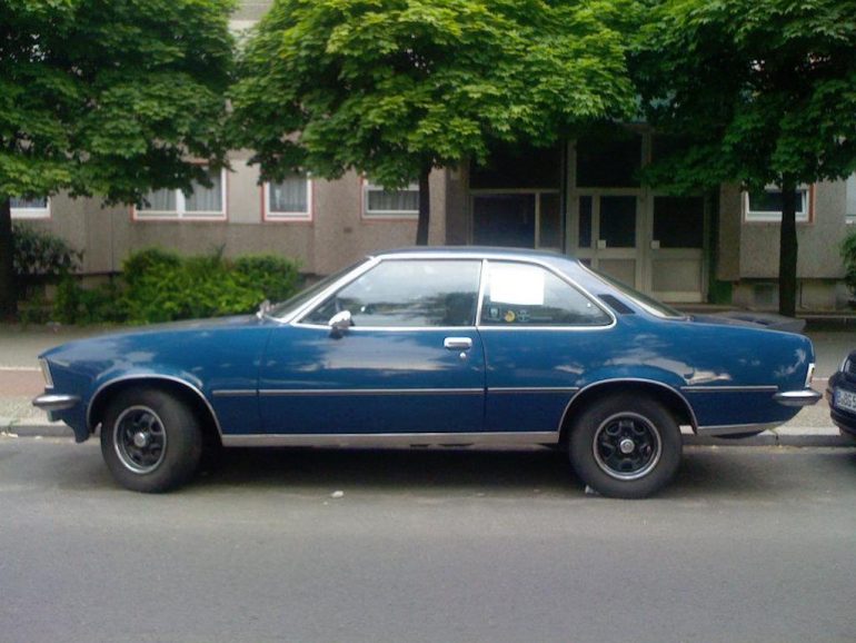 Oldtimer Berlin: Blaues Opel Commodore B Coupé vor grünen Bäumen
