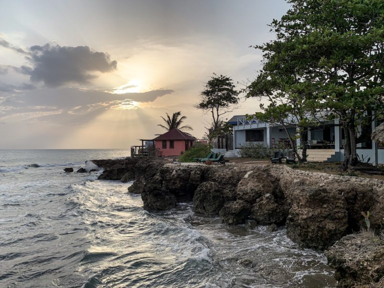 Jamaika Urlaub: Sonnenuntergang über Häusern und Felsen am Treasure Beach