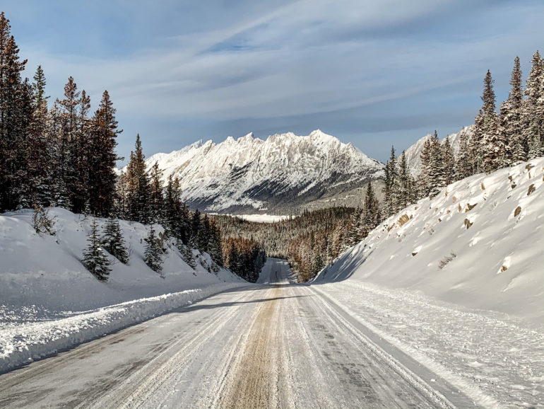 Alberta Highlights: Verschneite Strasse vor Bergen.