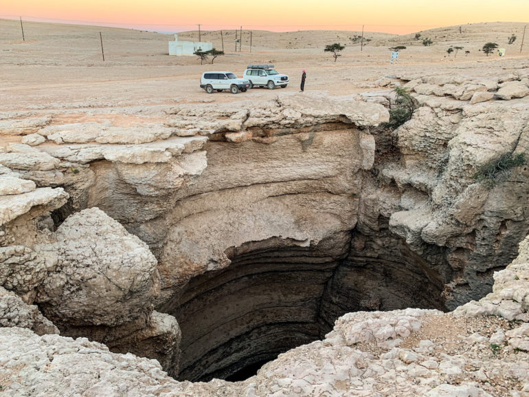 Autos vor einer Höhle im Oman
