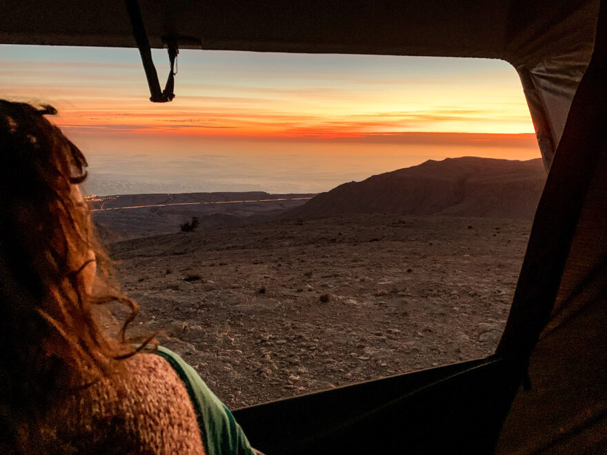 Frau blickt aus Dachzelt auf Oman Roadtrip