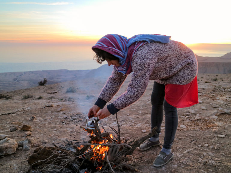 Frau bereitet Tee über Feuer zu
