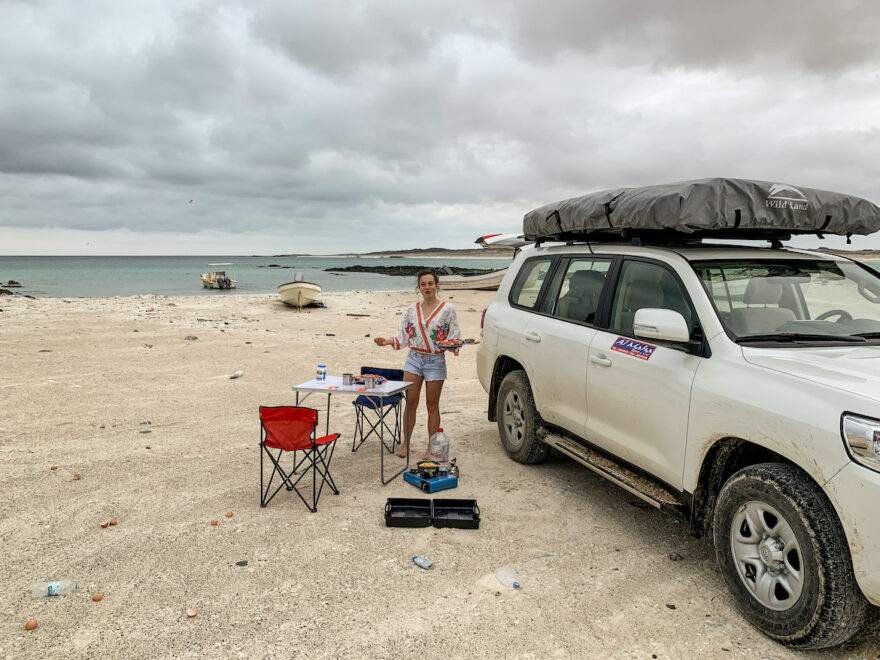 Frau mit Geländewagen am Strand im Oman