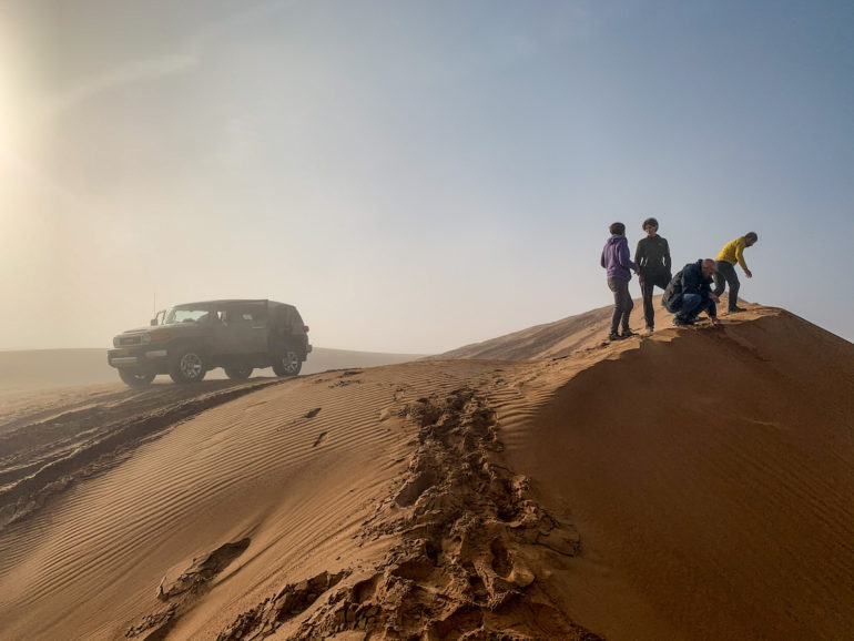 Geländewagen und Menschen in den Dünen von Sharquiya Sands